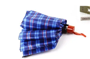 Vue détaillée du petit parapluie pliable à carreaux bleus avec poignée en bois.