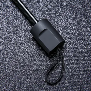Detalle del mango del paraguas plegable negro portátil compacto, protección solar anti-UV.