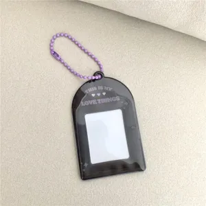 Detailed view of dark photocard holder with purple ball chain and English text print.