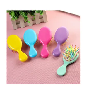 Détail de la mini brosse à cheveux colorée avec des picots en plastique et design portable.