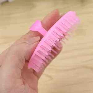 Détail de brosse de massage du cuir chevelu en plastique rose pour lavage des cheveux.