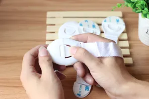 Verrou de sécurité pour tiroir d'enfant avec sangle en tissu et adhésif puissant de protection.