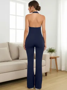 Back view detail of a solid navy blue halter neck backless tight jumpsuit in a living room.