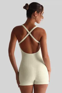 Detailed back view of a beige ribbed romper highlighting the elegant cross back straps and slim fit.
