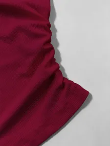 Dettaglio in primo piano di un top in maglia a costole rosso scuro, texture morbida ed elastica.