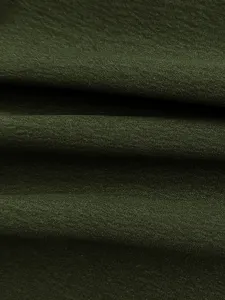 Close-up of dark green fabric texture, showing smooth draping and elegant clothing material details.
