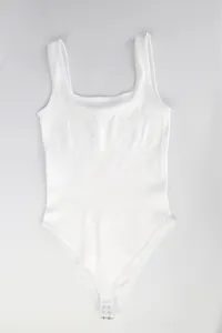 Body bianco a costine con scollo rotondo senza maniche, tutina basic senza cuciture.