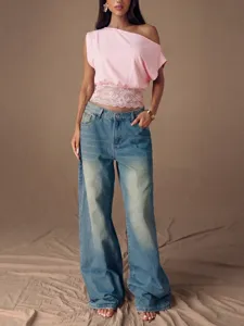 Detailansicht eines rosa One-Shoulder-Tops mit Spitzensaum und lässiger blauer Jeans.