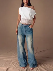 Weißes One-Shoulder-Oberteil mit feinem Spitzen-Saum und lässige Jeans Hosen präsentiert