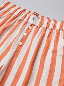 Close-up detail of women's orange and white striped casual shorts elastic waistband buttons.
