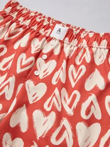 Detailed view of red shorts featuring white heart print, elastic waist and front buttons.
