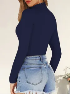 Detailed view showing the elegant dark blue high neck long sleeve slim fit top and denim shorts.