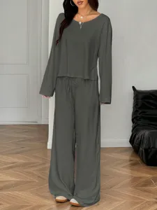 Details of the dark grey long sleeve top and loose wide leg lounge set worn in indoor setting.