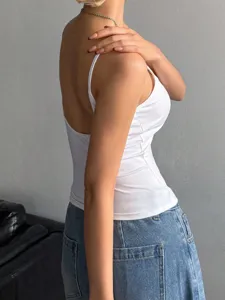 Vue détaillée d'un débardeur blanc dos nu, associé à un jean en denim et un collier fin.