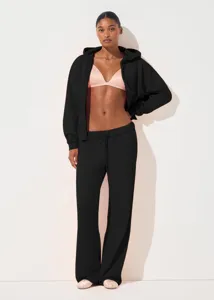 Detailed view of the black zip-up hoodie and sweatpants set worn by model in studio lighting.
