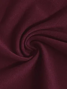 Close-up shot of soft burgundy knitted fabric with elegant swirl texture and fine textile details.