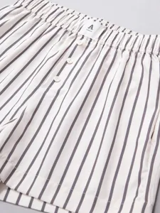 Close-up view of striped casual shorts with elastic waistband, buttons, and brand label.