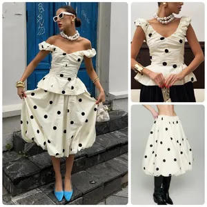 Ensemble deux pièces élégant à pois noirs et blancs avec haut col V et jupe boule midi.
