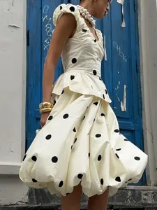 Ensemble chic à pois avec un haut sans manches à volants et une jupe midi bulle.