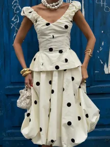 Ensemble deux pièces élégant à pois avec un haut à basque et une jupe midi style ballon.