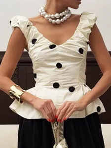 Vue détaillée du haut chic à pois sans manches avec col en V, volants et collier de perles.
