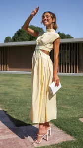 Detail shot of the yellow mock neck sleeveless cutout midi dress showing stylish street look.