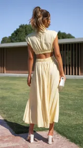 Back view detail of women solid yellow crop top and midi skirt set in outdoor street fashion.