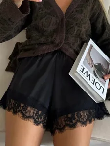 Detail shot of women's satin shorts featuring delicate black lace trim, high waist and soft fabric.