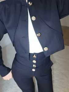 Detailaufnahme eines Damen Kurzblazers und hoher Hose mit goldenen Herzknöpfen im Set.