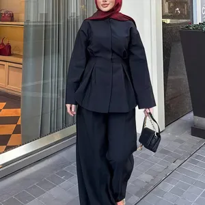 Detailansicht eines schwarzen Langarm-Oberteils und weiten Hosen, elegante Damenbekleidung.