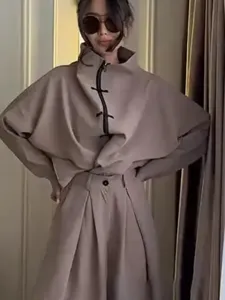 Detailed view of the chic beige two-piece outfit featuring a stand collar and wide-leg trousers.