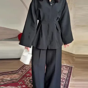 Detailansicht des eleganten schwarzen langärmligen taillierten Oberteils und Hosen-Sets.