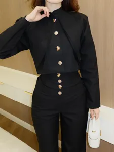 Nahaufnahme des eleganten schwarzen Stehkragen-Tops mit auffälligen goldenen Zierknöpfen.