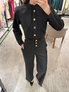Schwarzes Set aus Langarmtop mit Stehkragen und goldenen Knöpfen sowie hoher Hose.