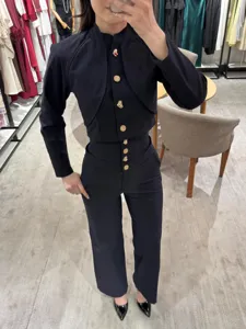 Eleganter schwarzer Zweiteiler mit Stehkragenjacke und High-Waist-Hose mit goldenen Knöpfen.