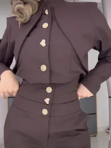 Detailansicht eines schicken dunkelbraunen Stehkragen-Tops und hoher Hose mit Knöpfen.