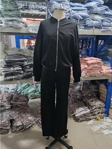 Vista detallada de chándal casual negro de dos piezas, chaqueta con cremallera y pantalon.