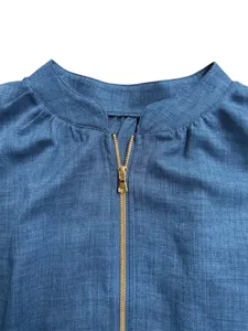 Close-up detail of a blue denim style women top, featuring a round neck and golden front zipper.