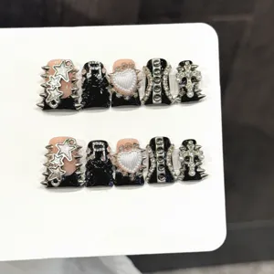 Closeup of gothic punk press-on nails featuring silver stars and rivets on black base.