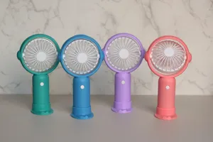 Gros plan de mini ventilateurs portatifs avec base de chargement en couleurs pastel.