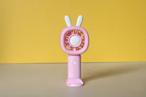 Detailed view of the pink mini handheld fan featuring cute rabbit ears and base stand.