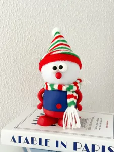 Close-up detail of a cute Christmas snowman night light with knit hat and scarf on a book.