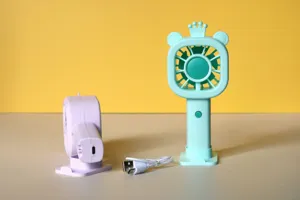 Dettaglio mini ventilatore USB portatile a mano con simpatico design orso corona e base di ricarica.