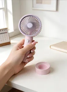 Primo piano della ventola portatile rosa sulla scrivania, design compatto e comoda ricarica USB.