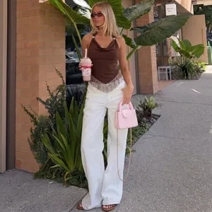 Outdoor street detail shot featuring a stylish brown halter cowl neck top with fringe hem.
