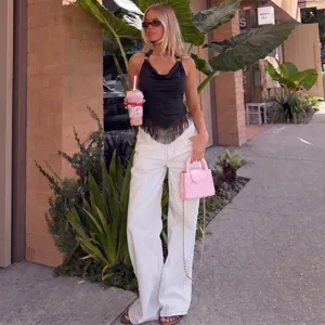 Outdoor street detail view of a stylish summer halter cowl neck top with fringe hem.