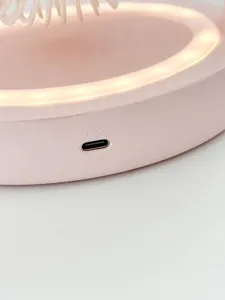 Gros plan sur le port de charge du ventilateur de bureau portable rose avec marquage clair.