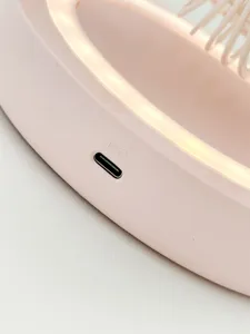 Vue en gros plan du port de charge d'un ventilateur de bureau rose avec anneau LED