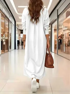Gedetailleerd achteraanzicht van een casual effen witte lange blousejurk in een moderne winkel.
