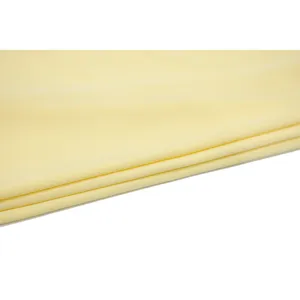 Detail view of soft light yellow chiffon fabric swatch, lightweight textile texture.